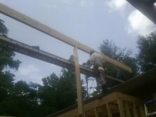 Carpenter setting a ridge beam over a new addition frame — Ice Dam Removal by Roofing Brothers in Middle Amana