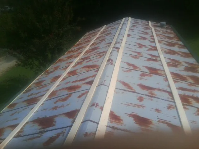 Rusted metal roof panels with new wood purlins before replacement — Storm Damage Roof Repair in Middle Amana by Roofing Brothers