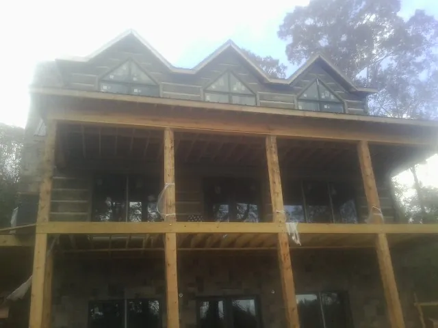 Dormers and porch framing on a large log home under construction — Roof Coating work by our crew in Middle Amana
