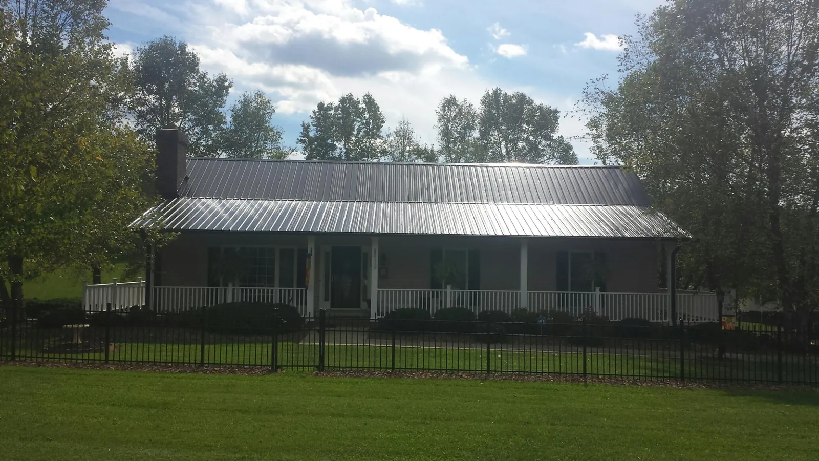 Gray metal roof on a brick ranch with a full width front porch — Gutter Guard Installation work by our crew in Middle Amana