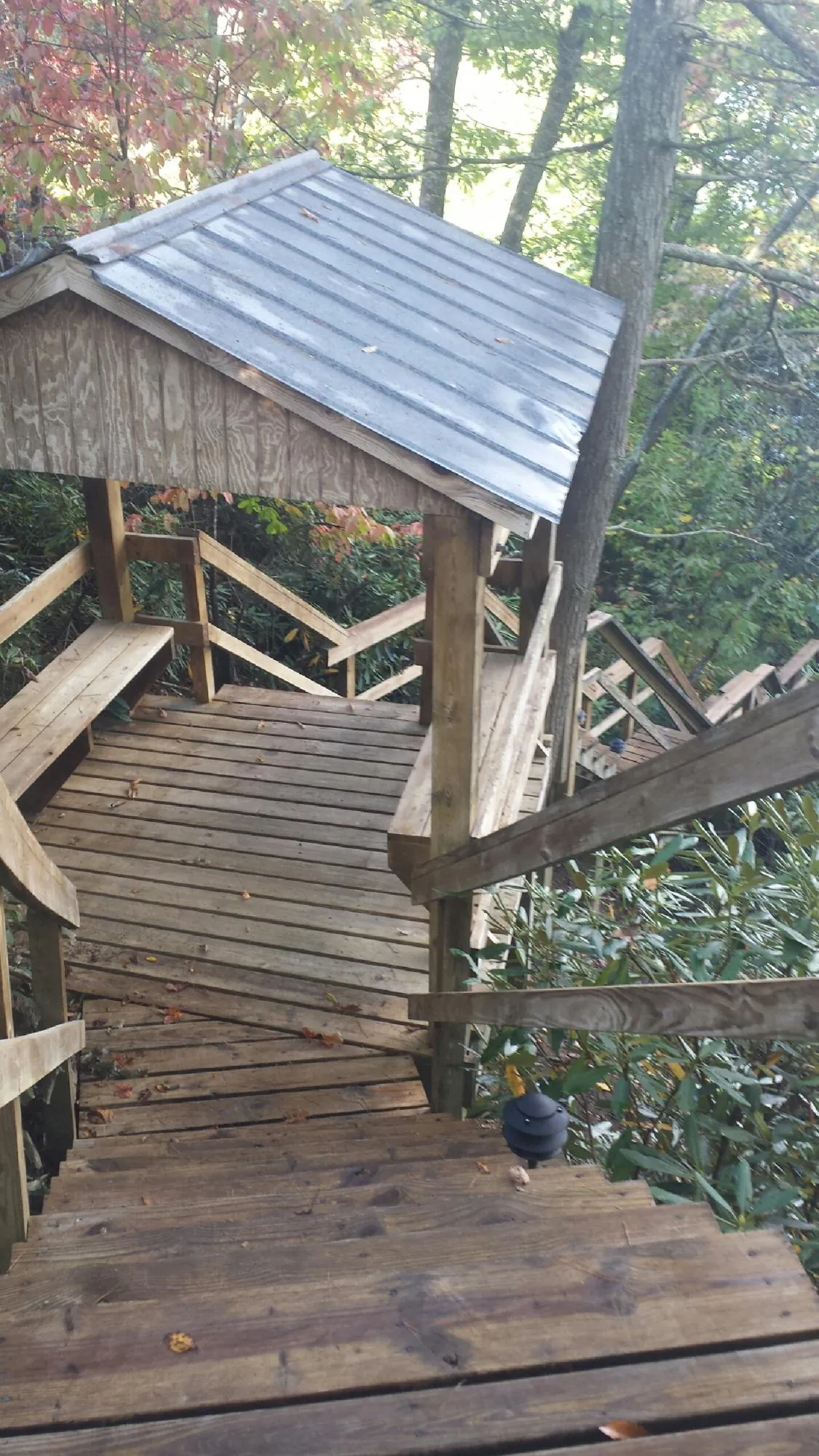 Metal roofed shelter over wooden steps on a wooded walkway — Skylight Repair & Installation work by our crew in Middle Amana