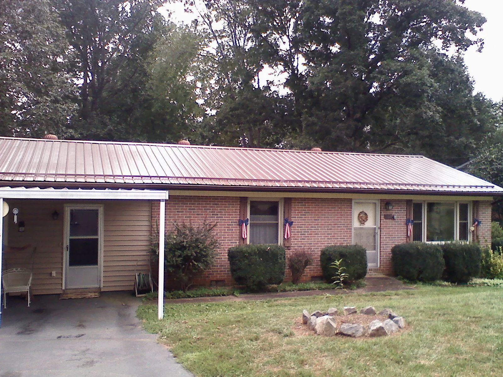 Bronze metal roof and carport on a brick ranch home — Roof Repair work by our crew in Middle Amana