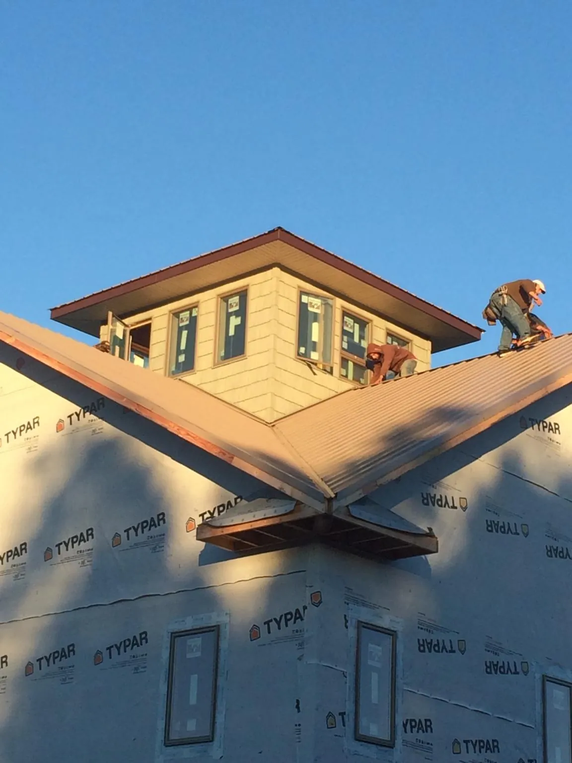 Roofers working around a rooftop cupola on a new metal roof at sunset — Roof Waterproofing in Middle Amana by Roofing Brothers